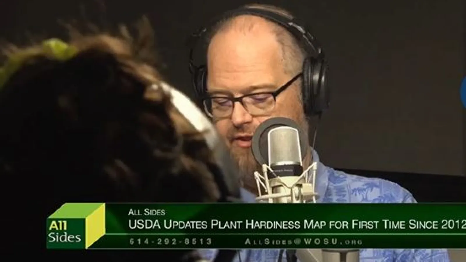 Aaron Wilson seated at a desk, for an interview with someone, in front of a mic with headphones.