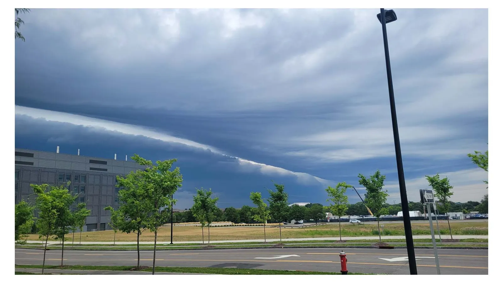 A view from a parking lot of a shelf cloud in the sky above a building 