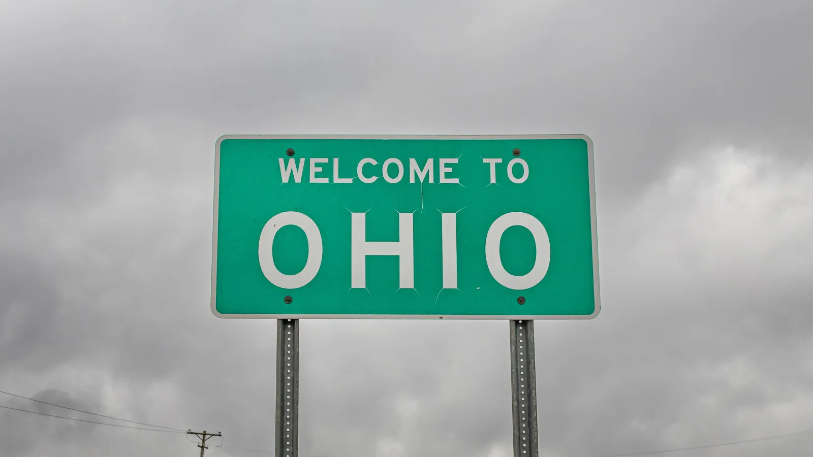 Ohio State Line Highway Sign against dark clouds.