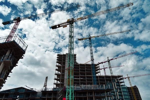 Cranes and building construction against blue sky and white clouds
