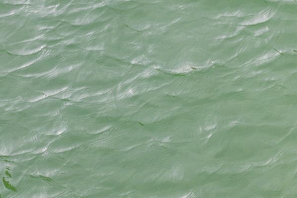 image from above of green body of water with light waves  