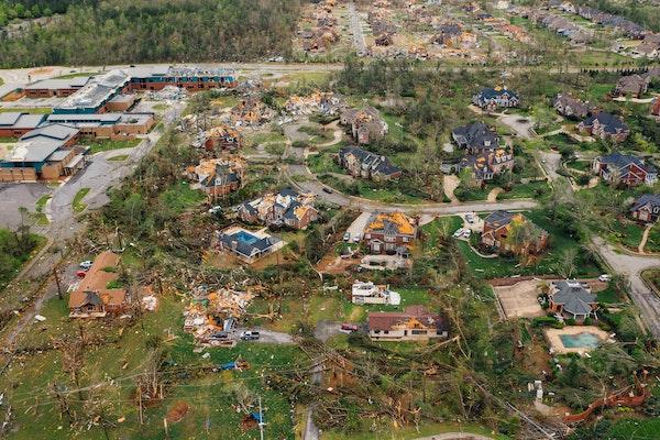Aerial image of a tornado-stricken subdivision with damaged trees and houses and downed wires