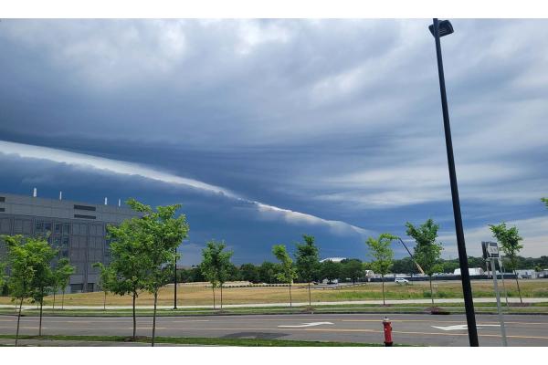 A view from a parking lot of a shelf cloud in the sky above a building