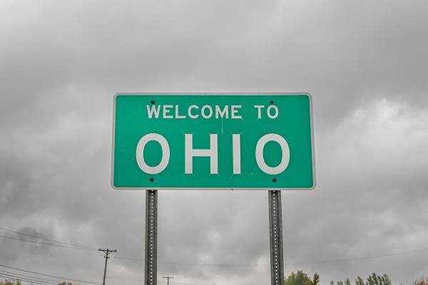 Ohio State Line Highway Sign against dark clouds.