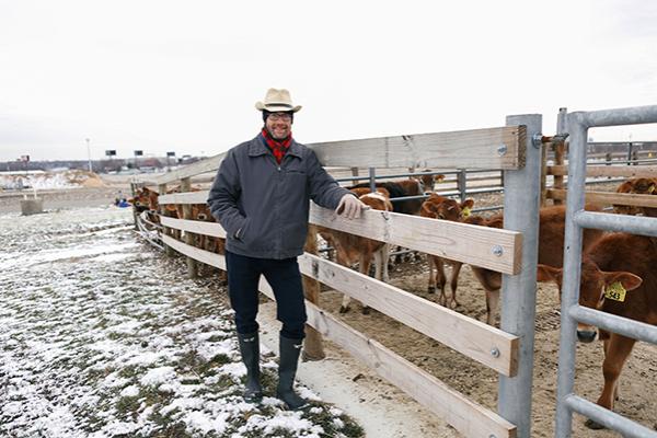 State Climatologist Bryan Mark stands in front of a line of dairy cows at Watermand Farm on a cold, cloudy February day. 
