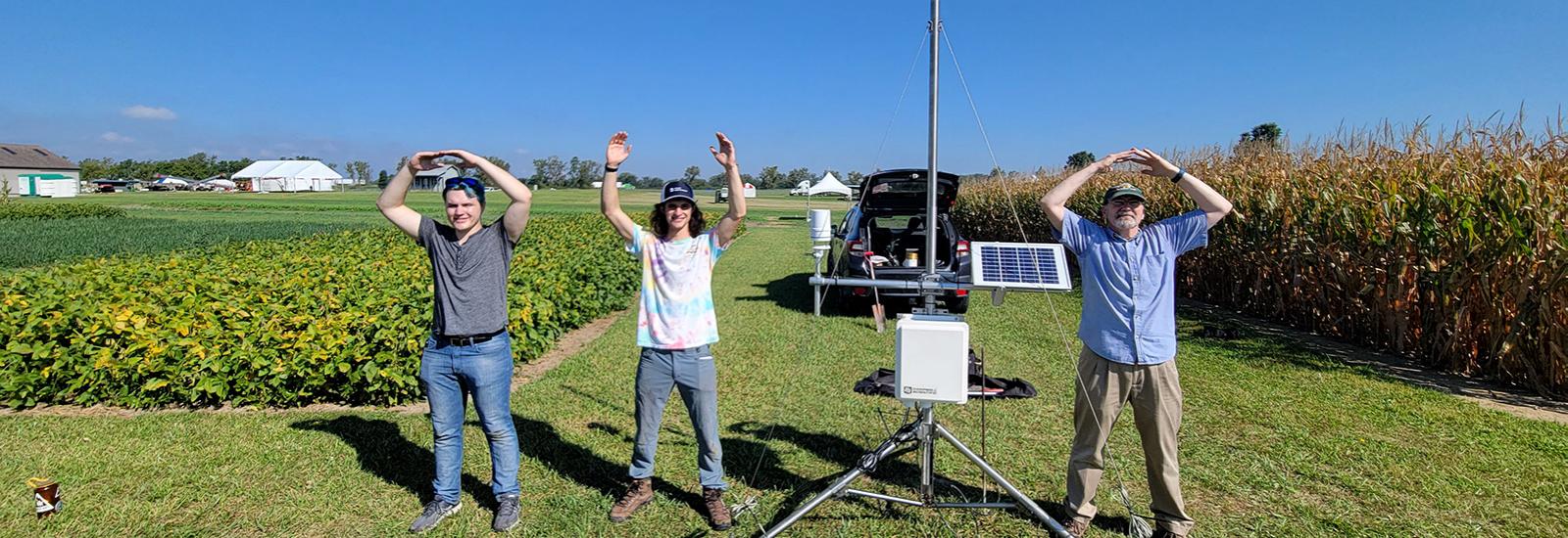 Jim DeGrand and students posing for O-H-I-O in front of a weather station